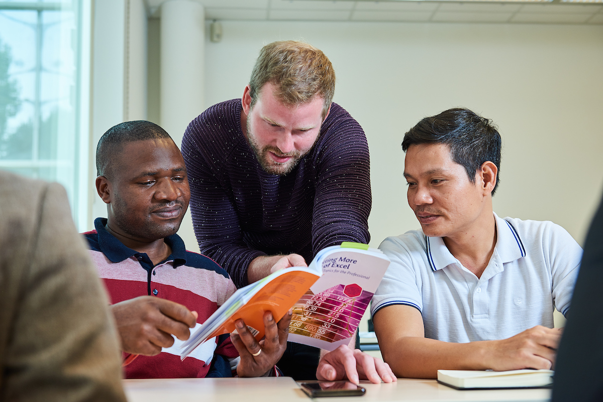 A teacher explains something using a textbook.